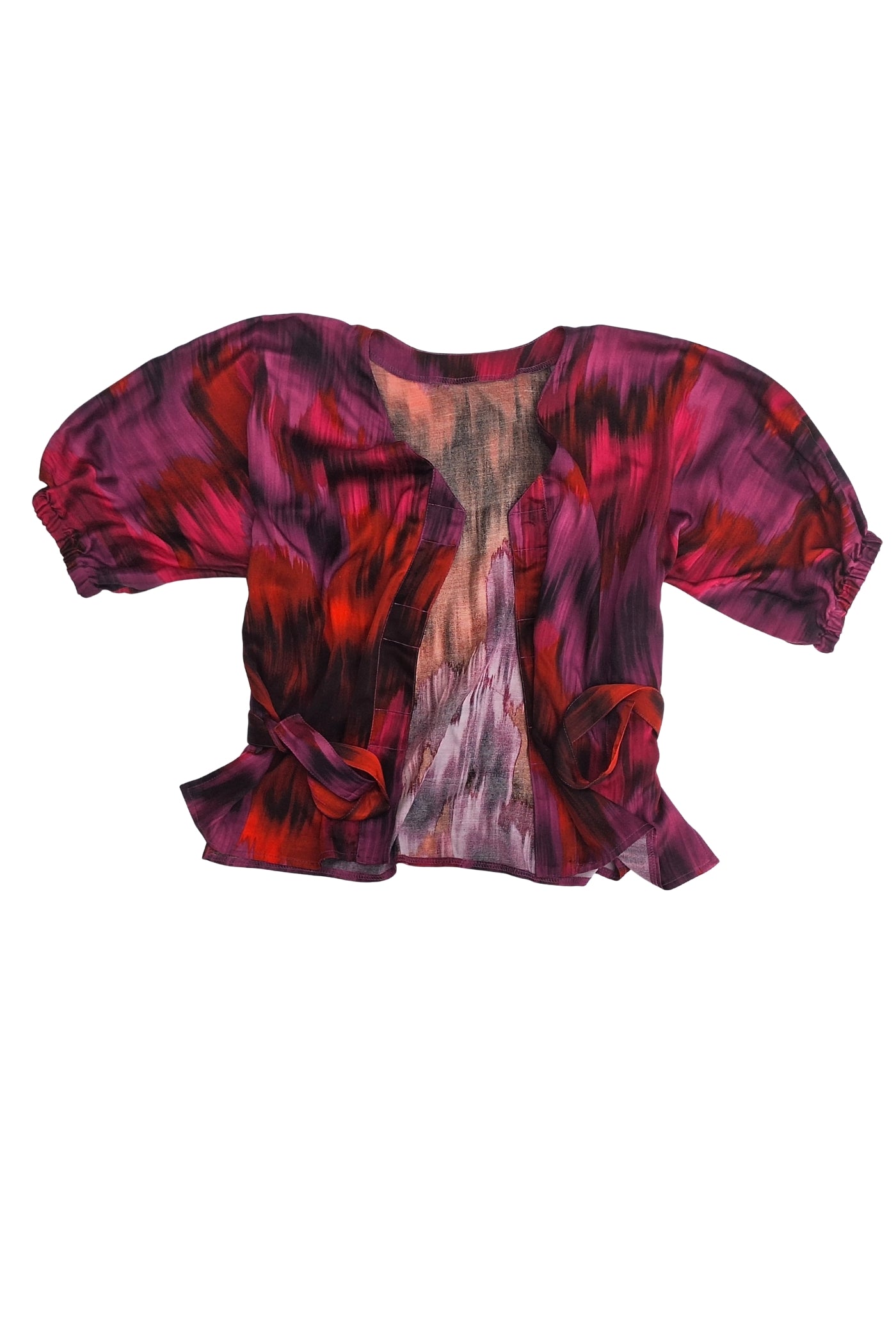Eine luxuriöse, adaptive Bluse aus 100% Viskose-Satin in leuchtenden Fuchsia-, Rot- und Lilatönen, mit Fledermausärmeln und einem passenden Gürtel. Die Bluse ist speziell mit drei Magnetverschlüssen ausgestattet, was sie ideal für Menschen mit Tetraplegie oder eingeschränkter Handfunktion macht.